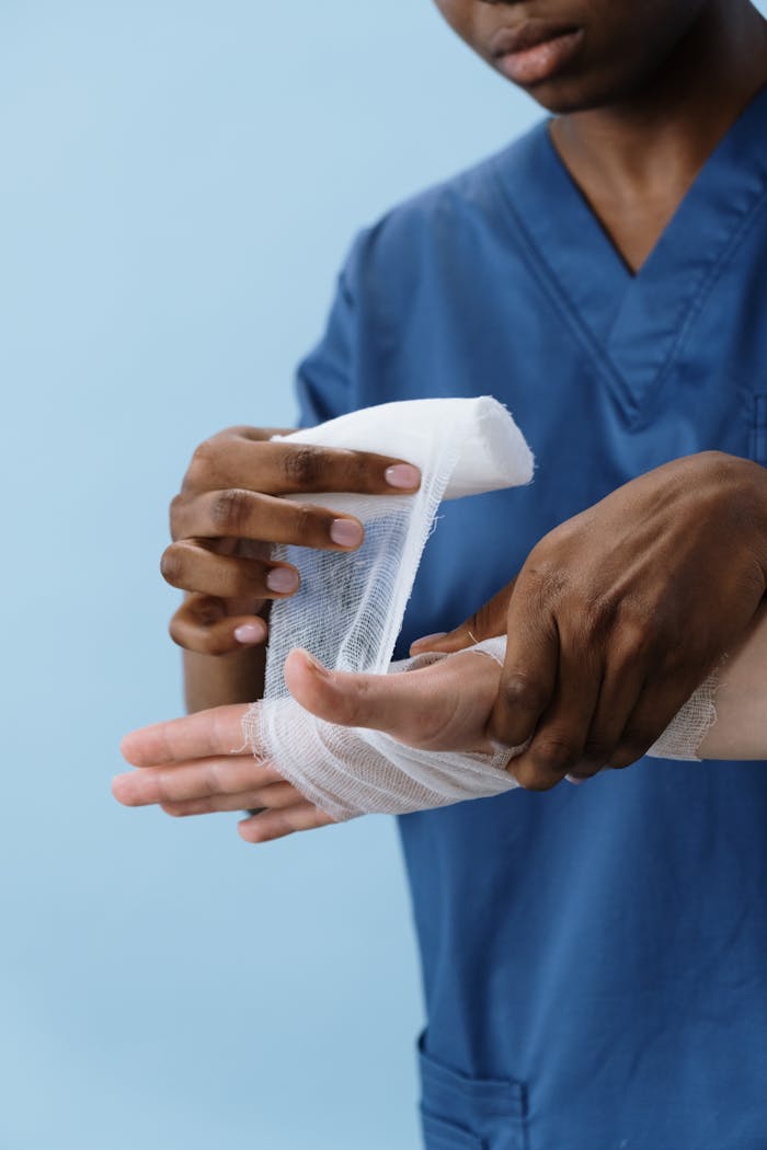 about-header A healthcare professional wrapping a patients hand with gauze for injury care.